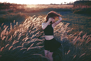 woman in black crop top and skirt surrounded by grass field during daytime