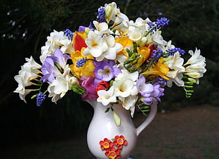 multi-colored flower in white ceramic pitcher