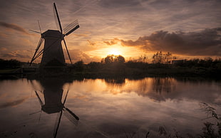 silhouette photo windmill beside body of water