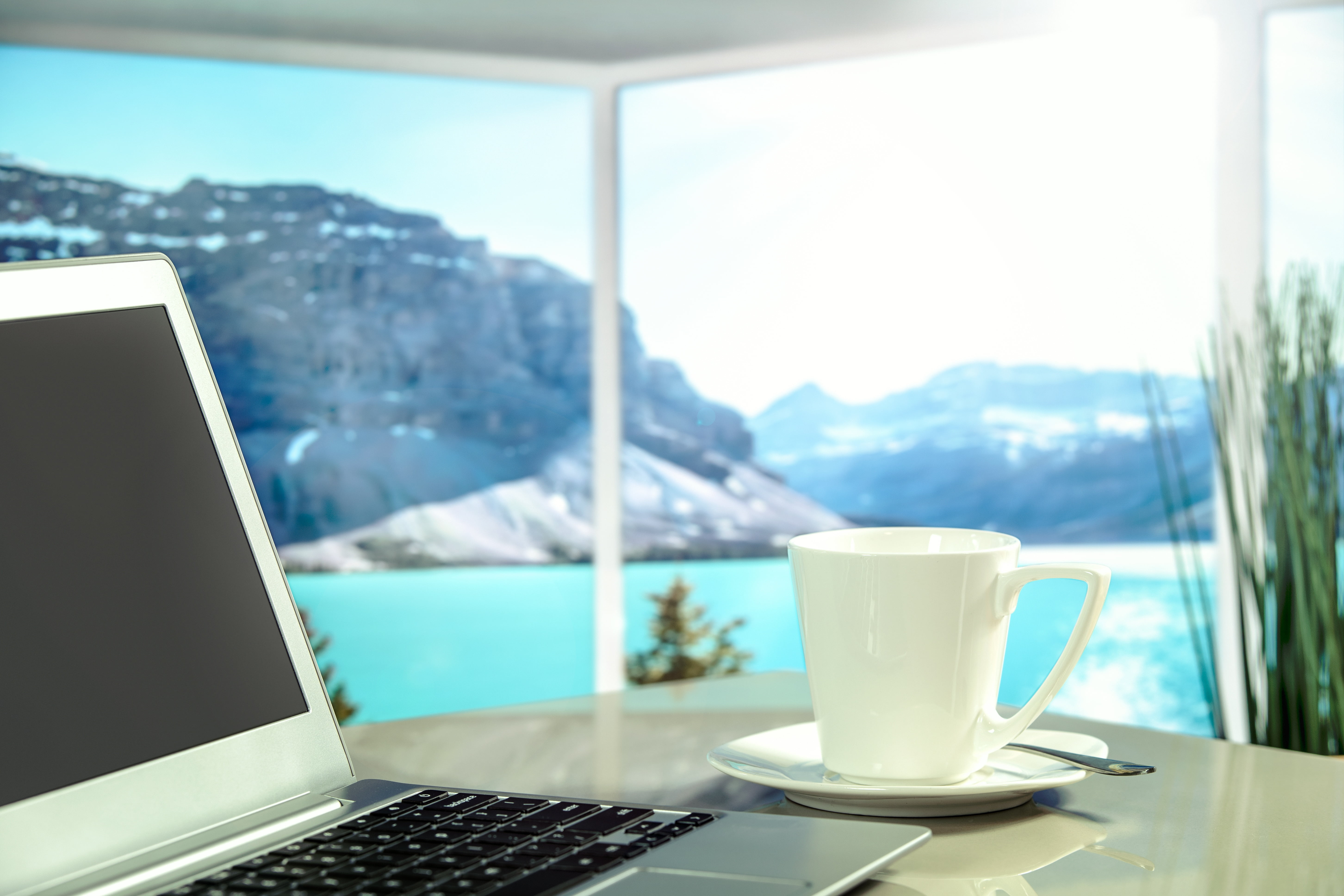 silver laptop computer beside white ceramic teacup