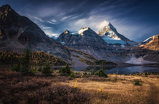 rock mountain near body of water under gray sky