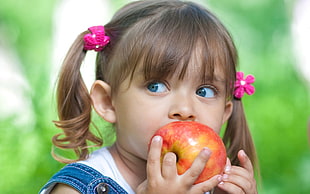 selective focus photography of child biting apple