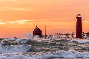 ocean waves near red light house during sunset