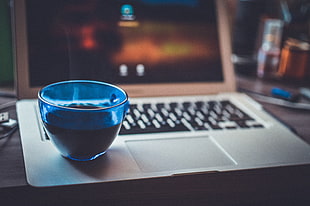cobalt glass filled with black liquid on gray laptop computer
