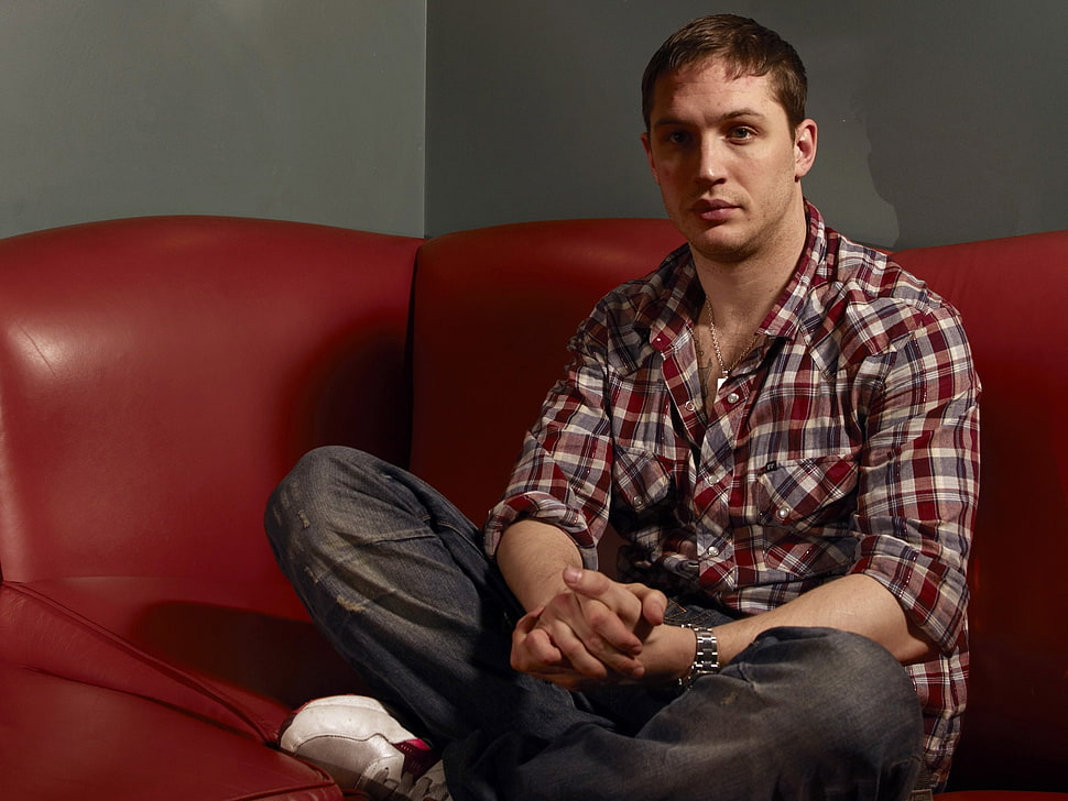 man in red and blue flannel shirt sitting on red leather couch HD wallpaper