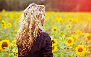 women wearing black jacket near sunflower field