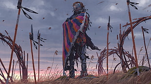 man in blue and pink scarf standing on withered grasses