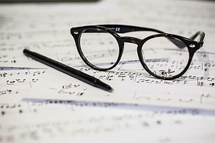 black framed eyeglasses beside black pen