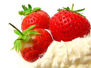 three red strawberries on white cream