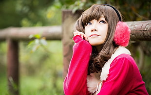 close up photo of a woman wearing red fur headphones wearing red coat looking up
