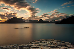 photo of blue body of water under cloudy sky