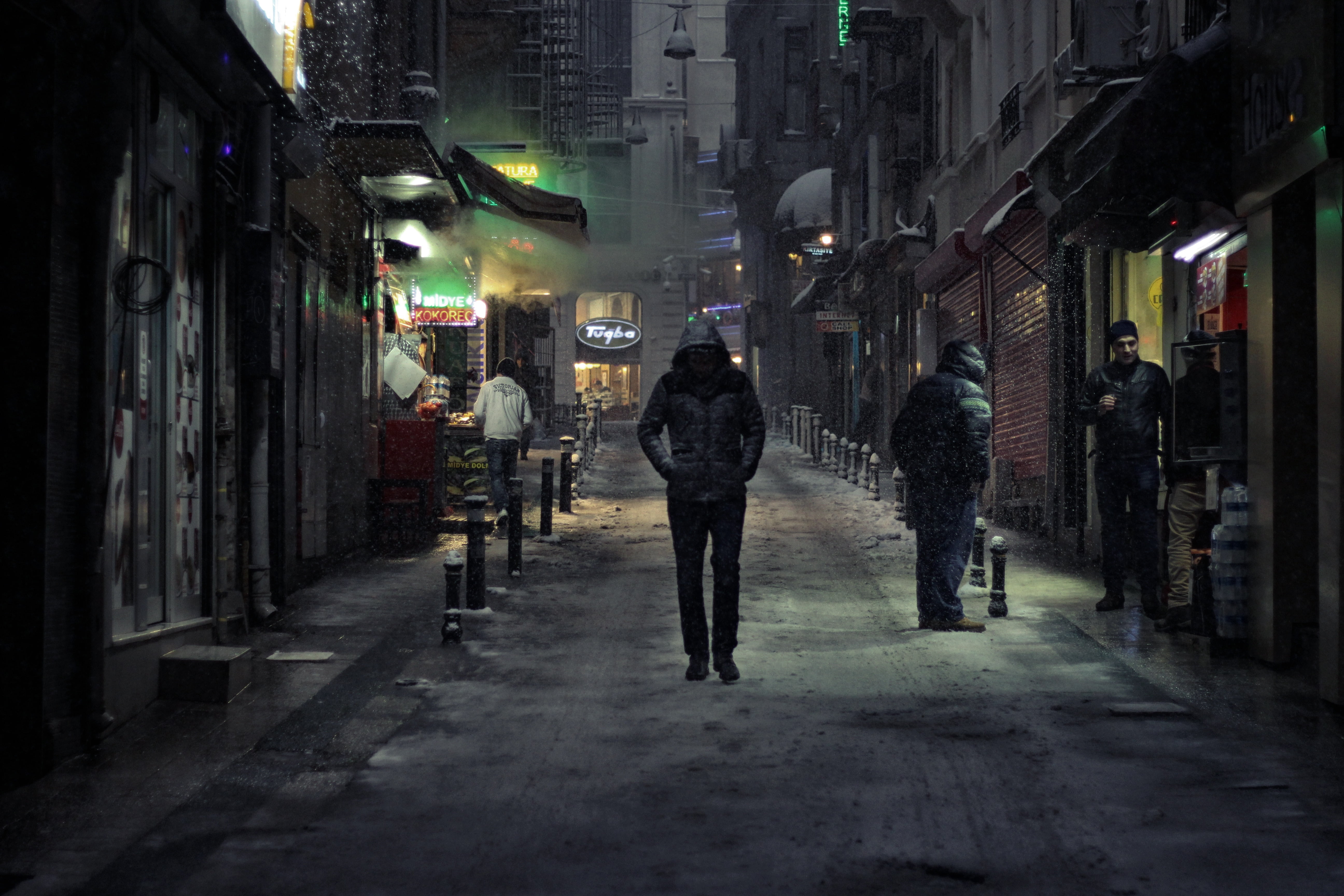 man wearing black hoodie standing between high rise buildings