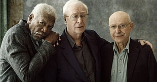 Morgan Freeman with two men wearing suit jackets beside him