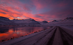 landscape photography of snow-capped road and mountain ranges during sunset