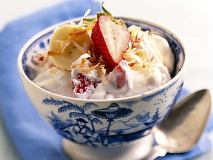 sliced fresh fruits with white cream on white and blue ceramic bowl