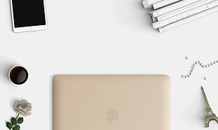white smartphone and MacBook on top of white surface