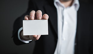 selective focus photography of person holding white card