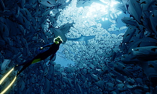 person in black and green diving suit underwater surrounded by sea-creatures