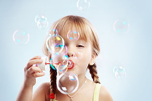 girl in yellow sleeveless top playing water bubbles