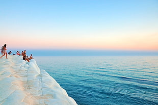 group of people sitting on sea side cliff