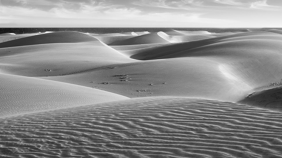 grayscale of sand dune under cloudy sky HD wallpaper