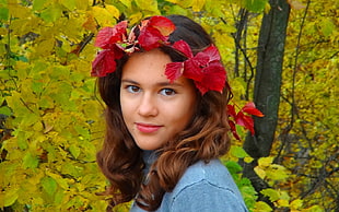 woman wearing blue top and red flower headband beside trees