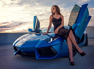 woman wearing black lace dress sitting on blue Lamborghini car