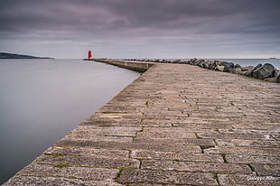 landscape photography of person standing at the end of concrete breakwater bridge, dublin, ireland