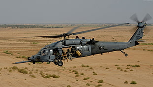 gray helicopter flying over desert at daytime