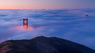 landscape photo of red steel bridge covered in clouds