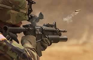 selective focus photography of person holding black assault rifle HD wallpaper