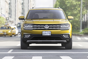 selective focus photography of yellow Volkswagen SUV passing through crossing during daytime
