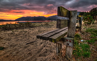 brown wooden bench under gray and orange cloudy sky during daytime HD wallpaper
