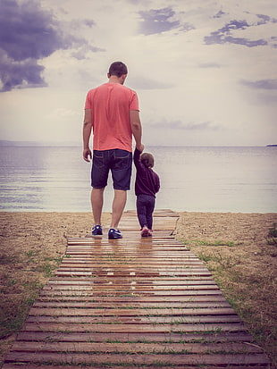 father and son picture beside body of water HD wallpaper