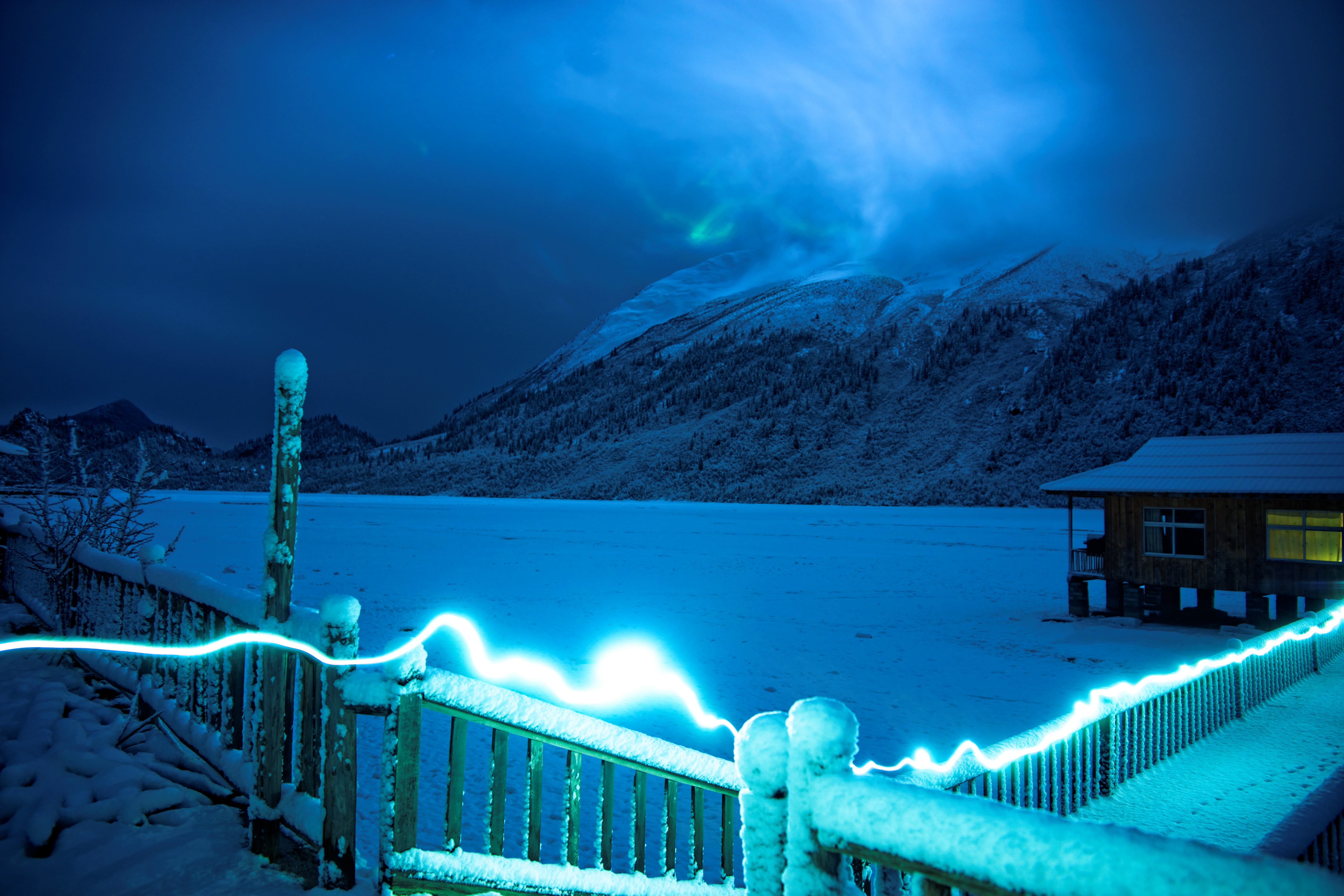 time lapse photo of string light near bridge and house on snow