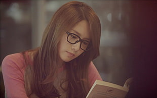 brown haired woman wearing black eyeglasses reading book