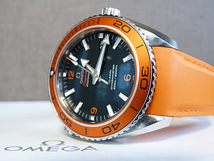 round orange Omega analog watch with orange leather strap