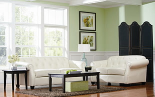 tufted white fabric sofa set with black wooden coffee table near white wooden frame window inside room