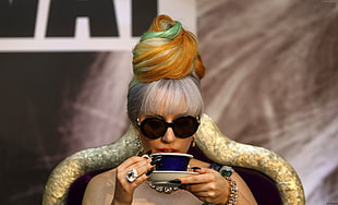woman wearing black sunglasses drinking from cup while sitting