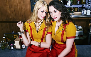 two women wearing yellow-and-red short-sleeved dresses taking selfie inside room