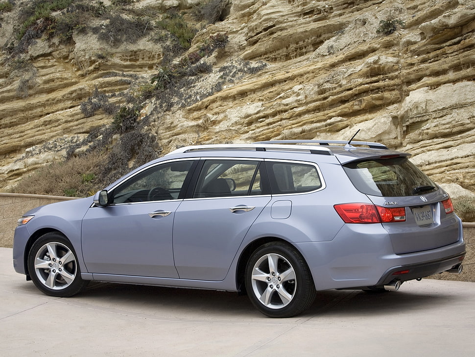 blue SUV parked beside brown concrete rock HD wallpaper