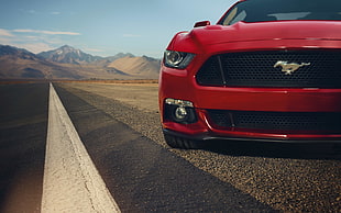 red Ford Mustang on highway with view of mountain during daytime