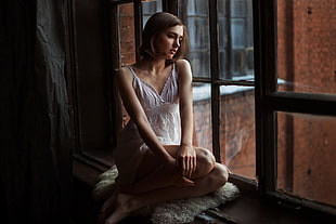 woman looking down sitting near window