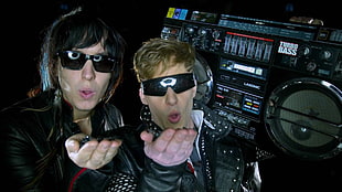 two men wears black sunglasses beside black subwoofer speaker