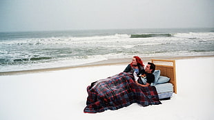 man and woman lying on bead near seashore during daytime