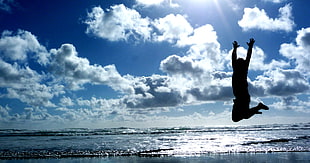 silhouette photography of  person jumping near beach shore during daytime HD wallpaper