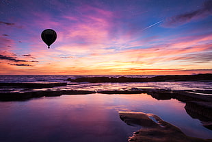 hot air balloon above body of water at sunset HD wallpaper