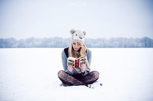 woman reading book in the middle of snow field HD wallpaper