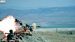 soldiers firing guns near mountain during daytime
