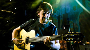 man playing acoustic guitar under green lights